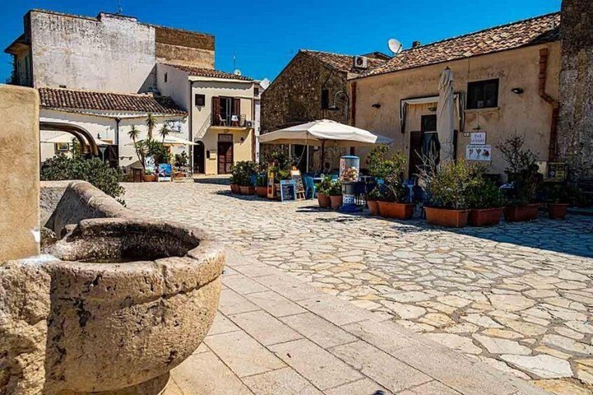 Un patio empedrado con edificios, mobiliario de exterior y plantas en macetas. 5