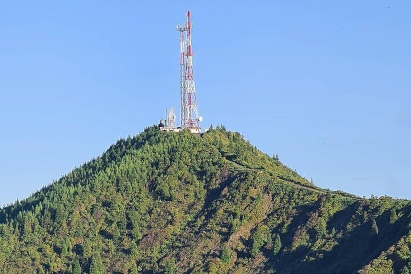 A telecommunications tower on a hill with dense forest. 1