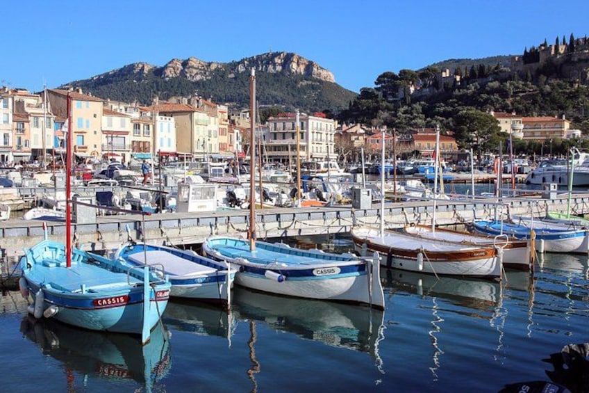 A marina with boats docked, a bridge, and buildings in the background. 1