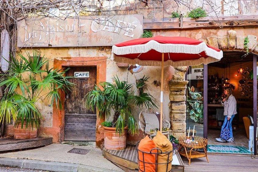 A cafe with a red umbrella, potted plants, and a staircase leading to the entrance. 4