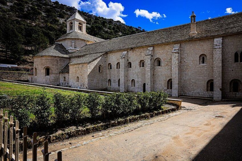 A stone building with a bell tower, surrounded by a gravel path and greenery. 5