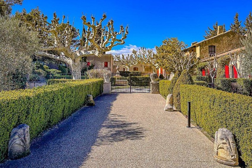 A gravel pathway leading to a gated entrance, flanked by neatly trimmed hedges and trees. 4