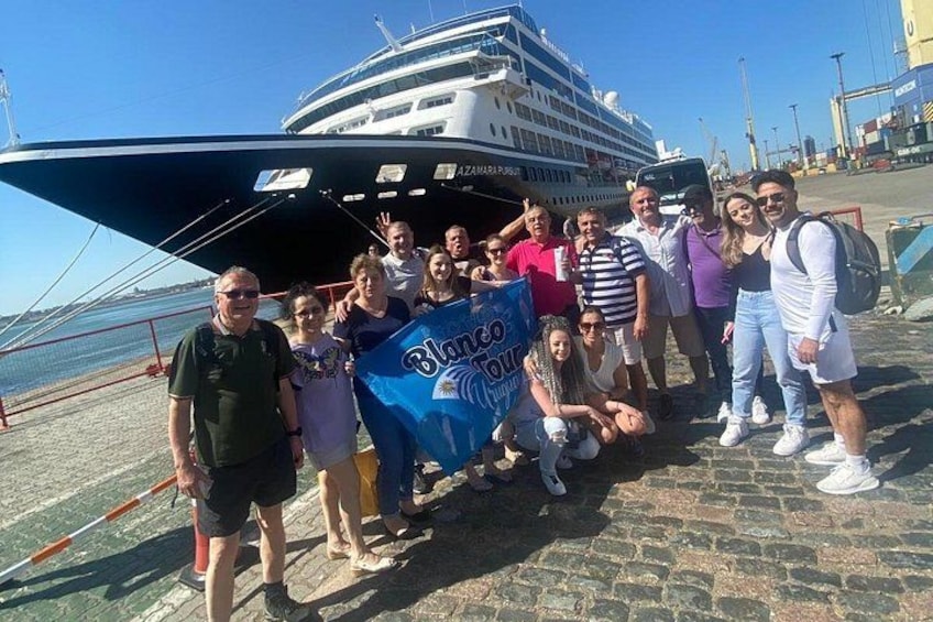 A group of people posing in front of a cruise ship with a banner. 2