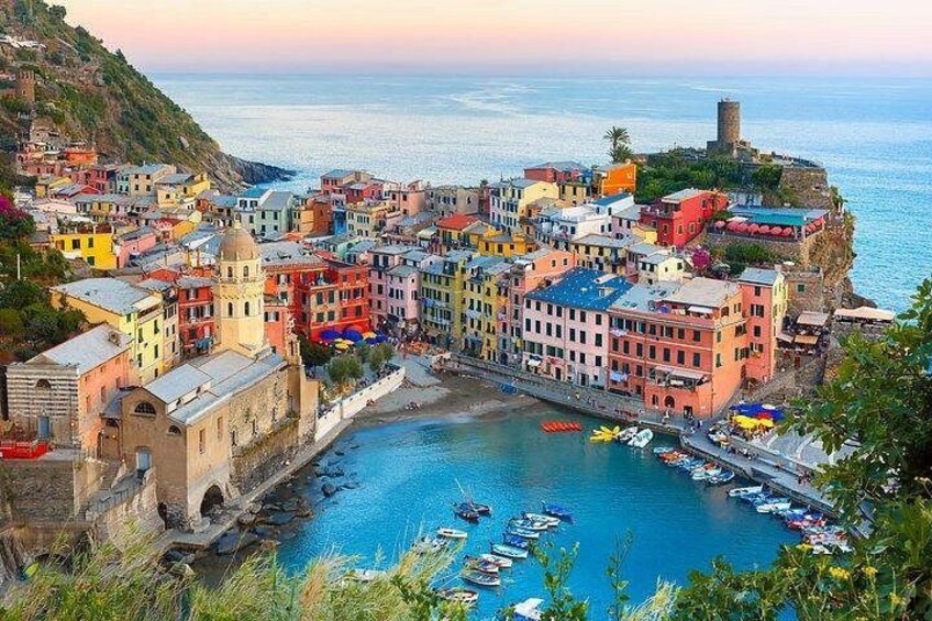 Une ville côtière aux bâtiments aux couleurs vives, un port où sont amarr és des bateaux et une falaise qui surplombe la mer. 1