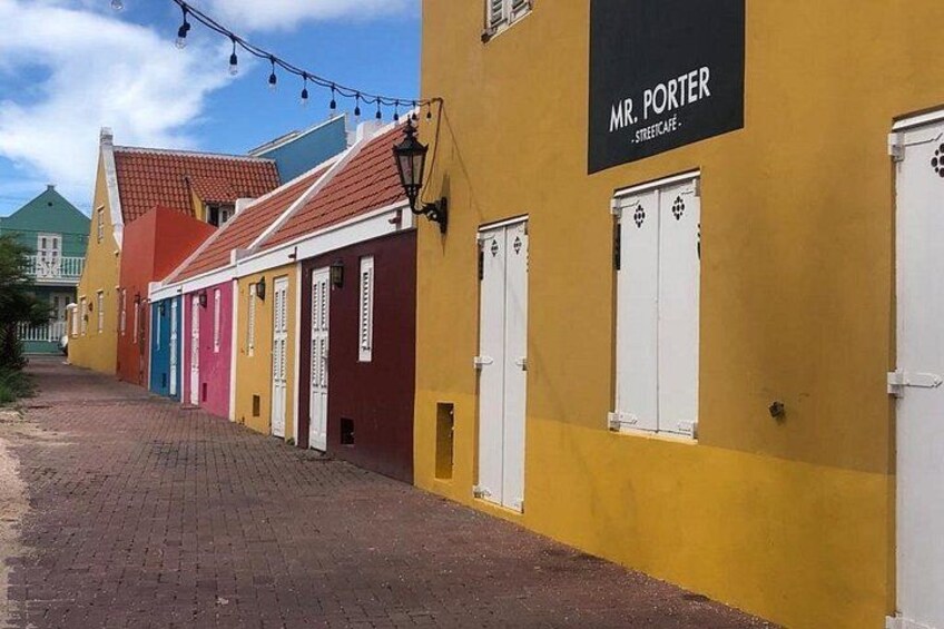 A street with colorful buildings and a sign for 'Mr. Porter Street Cafe.' 1