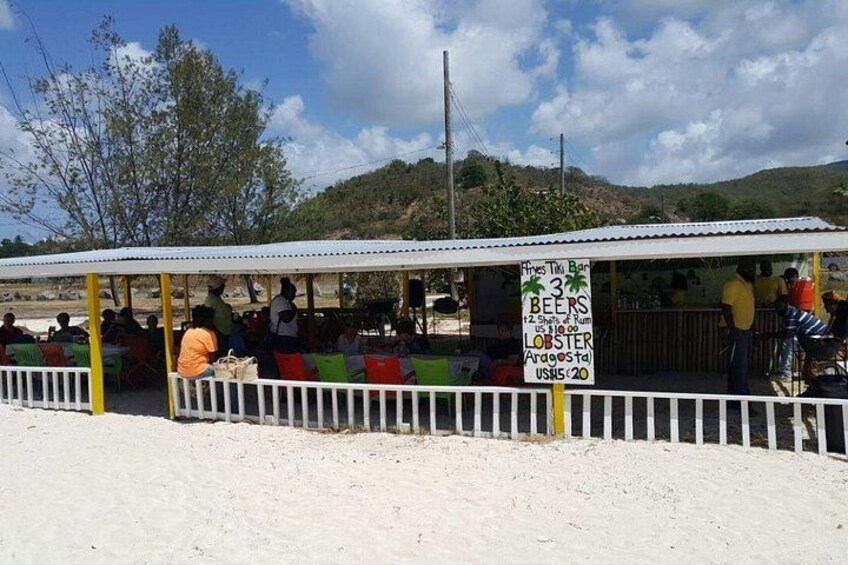 Un puesto de comida en la playa con un cartel que anuncia cervezas y langosta. 3