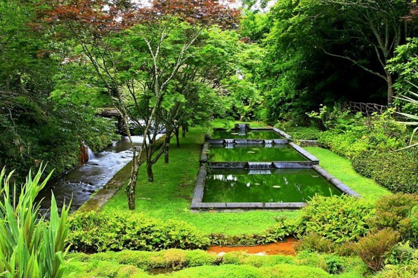 A serene garden with a pond, lush greenery, and a small waterfall. 2