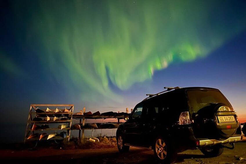 Un véhicule garé la nuit, avec des aurores boréales en arrière-plan. 2