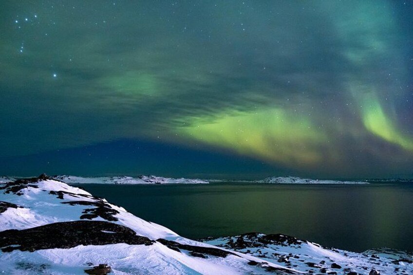 Un paysage enneigé avec une étendue d’eau calme et des aurores boréales. 4