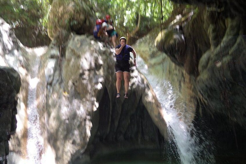 A person rappelling down a rocky cliff with water flowing below. 3