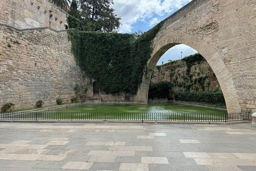 A stone bridge with an arch, a paved area, and a small water feature. 3