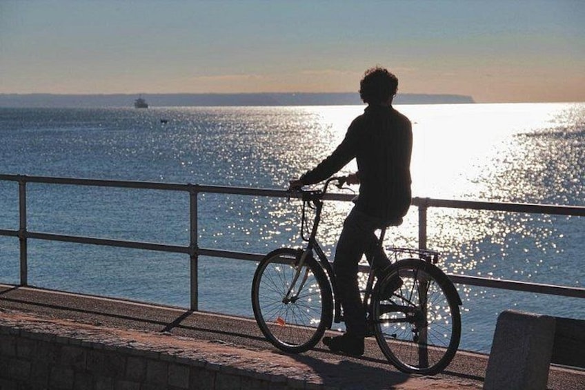 Une personne à vélo, au bord de l’eau, au coucher du soleil. 3
