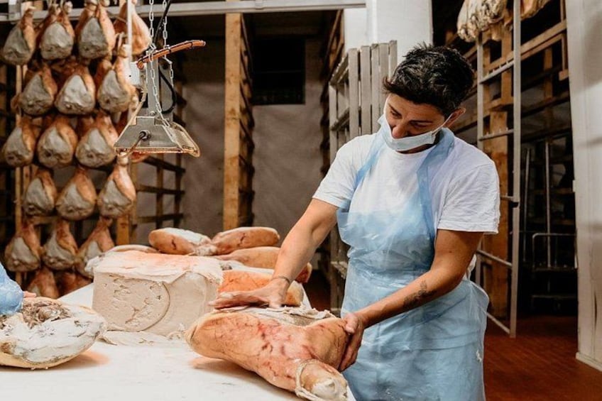 A person in a white shirt and blue apron handling large loaves of bread in a bakery. 1