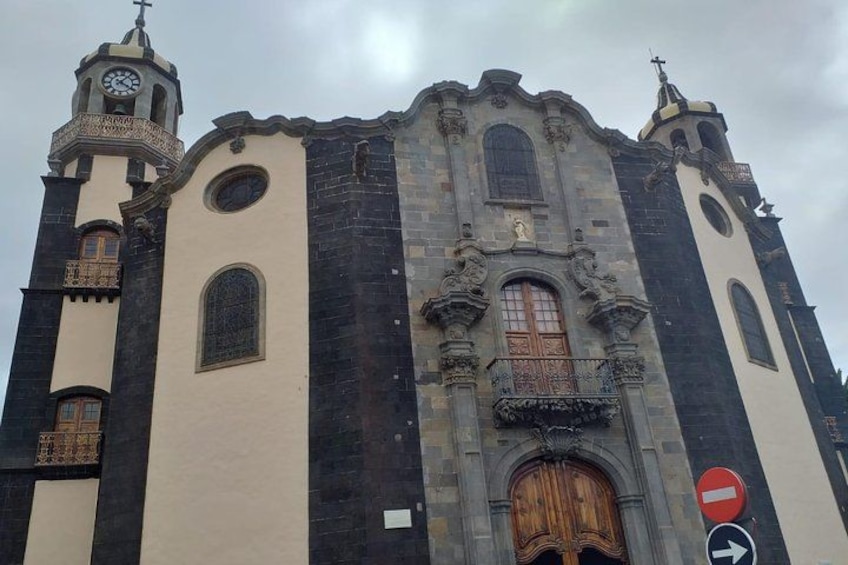En historisk kirke med et tårn, dekorative vinduer og en stor trædør. 4