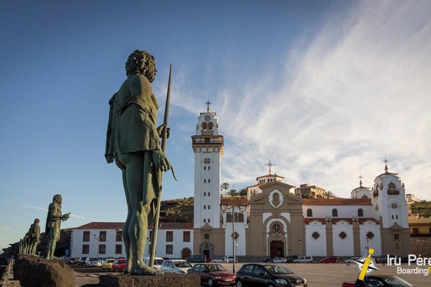 En statue af en figur med et sværd, en kirke med et kirketårn og en klar himmel. 1