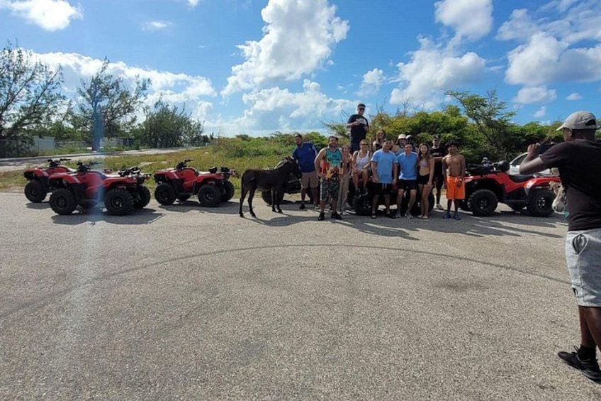 A group of people standing in a parking lot with ATVs and a horse. 2