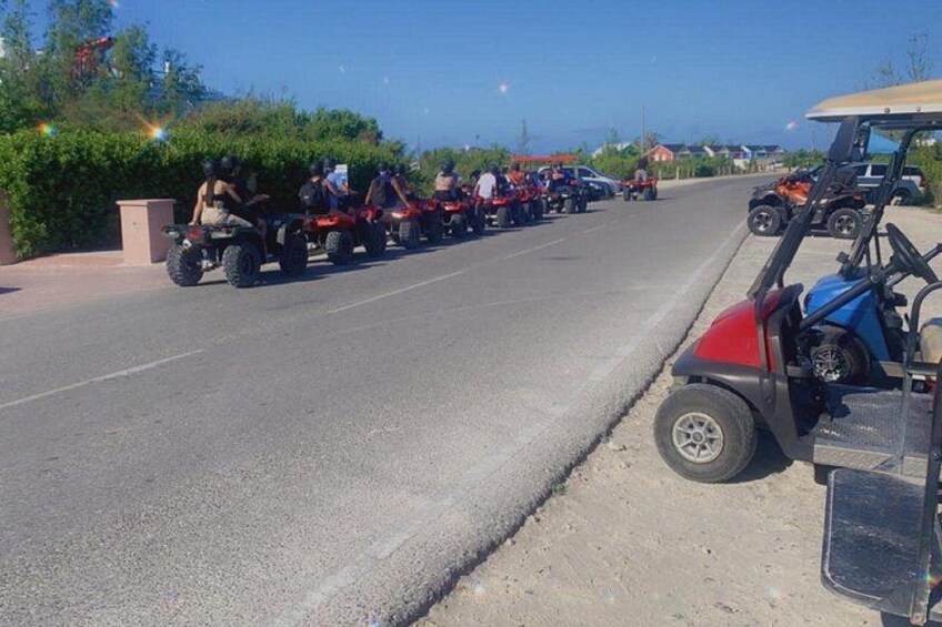 A road with a line of red ATVs and a golf cart parked on the side. 3