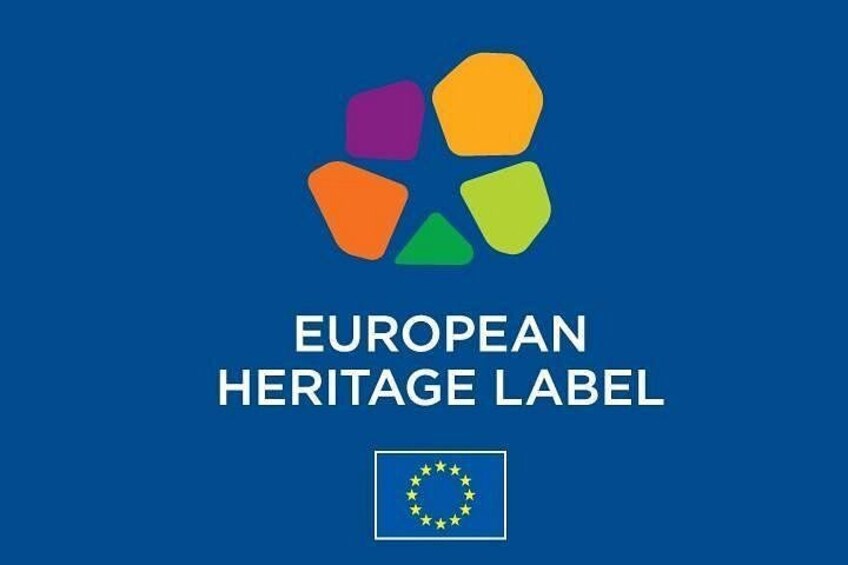 The European Heritage Label logo with a blue background and a flag with stars. 2