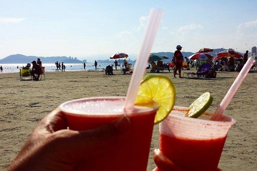 Ein Strand mit Menschen, Sonnenschirmen und Getränken. 3