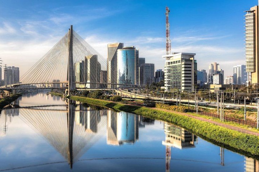 A modern cityscape with a prominent cable-stayed bridge, skyscrapers, and a calm river reflecting the structures. 4