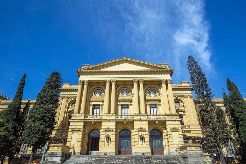 A classical building with columns and a pediment, surrounded by trees. 5