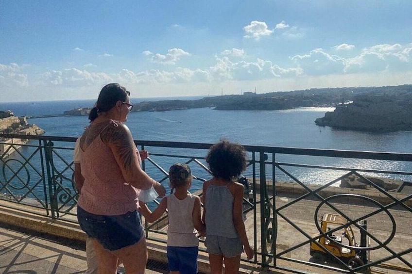 A woman and two children looking at the sea from a balcony. 5