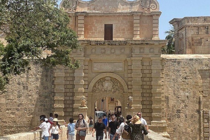 A historic stone building with an arched entrance and statues. 4