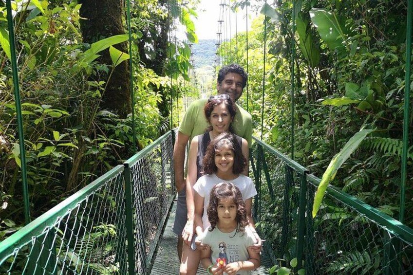 A group of people on a suspension bridge surrounded by dense greenery. 2