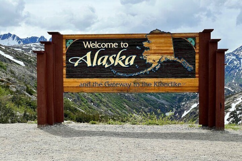 A wooden sign with 'Welcome to Alaska and the Gateway to the Klondike' written on it. 3