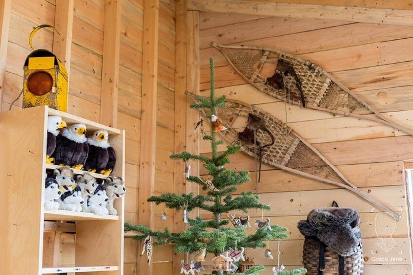 A wooden interior with a Christmas tree, a shelf with stuffed animals, and a bear sculpture. 4