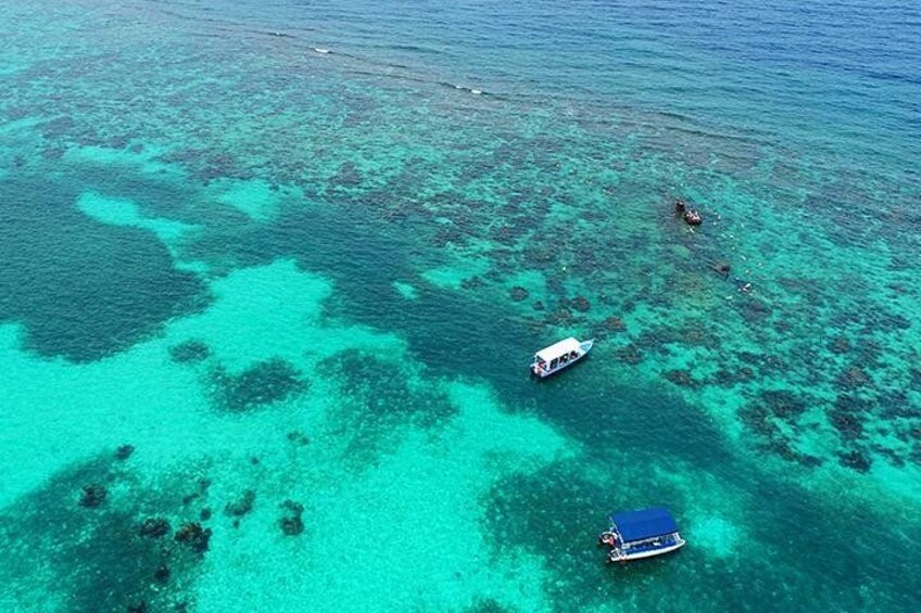 Un mar turquesa con barcos y arrecifes de coral. 1