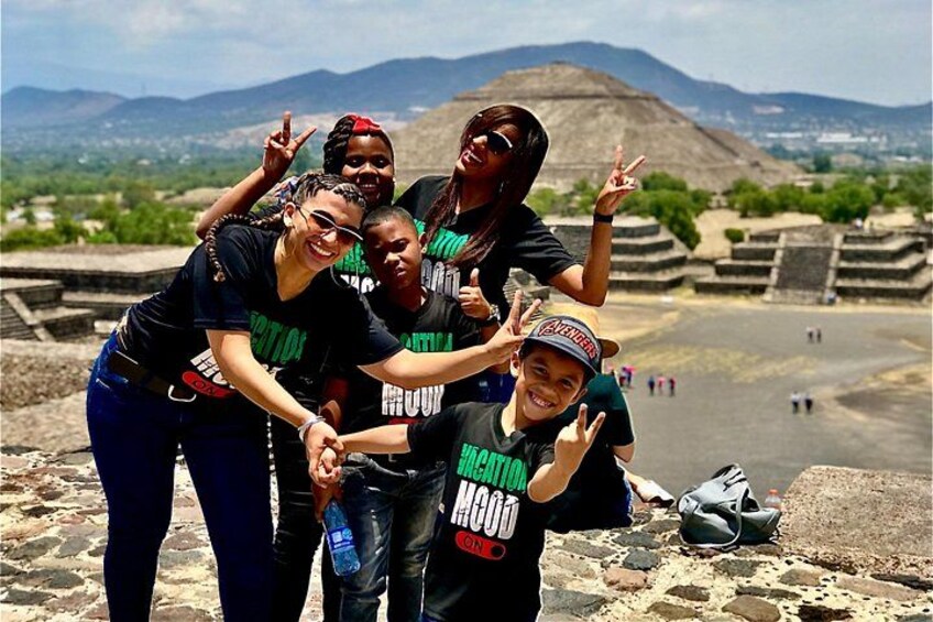 A group of people posing in front of ancient ruins with a mountain in the background. 1