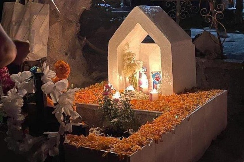 Un santuario con techo blanco, velas, flores y ofrendas. 5