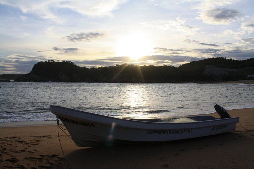 Un bote en la playa con el sol poniéndose al fondo. 3