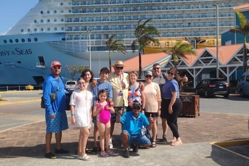 A group of people posing in front of a cruise ship named 'SONY THE SEAS' with palm trees and a building in the background. 4
