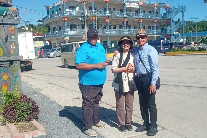 Three people standing on a sidewalk with a building in the background. 3