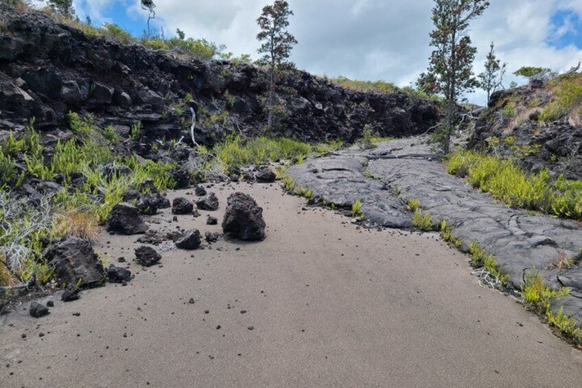 A winding road through a volcanic landscape with scattered rocks and sparse vegetation. 2