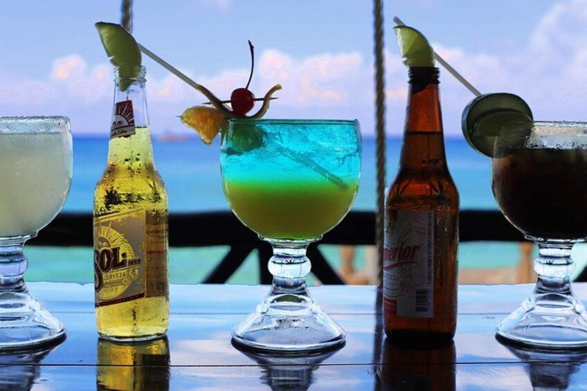 Three cocktails on a table with a view of the ocean. 3