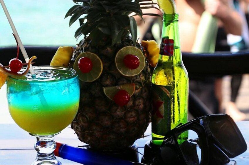 A pineapple with a drink and a bottle on a table. 2