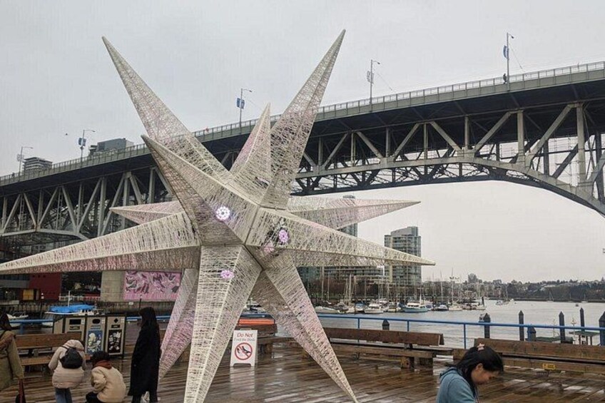 En stor stjernelignende skulptur med tekst, en bro i baggrunden og en havnefront. 5