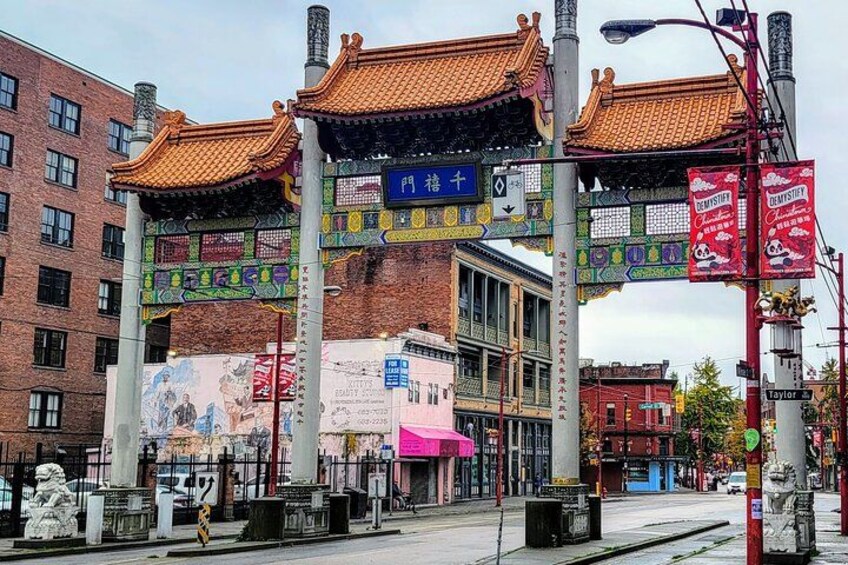 Une structure architecturale chinoise traditionnelle, agrémentée d’une enseigne, entourée de bâtiments modernes et de panneaux de signalisation. 5