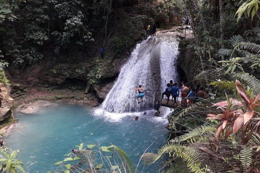 A waterfall, a pool of water, and people around the area. 3
