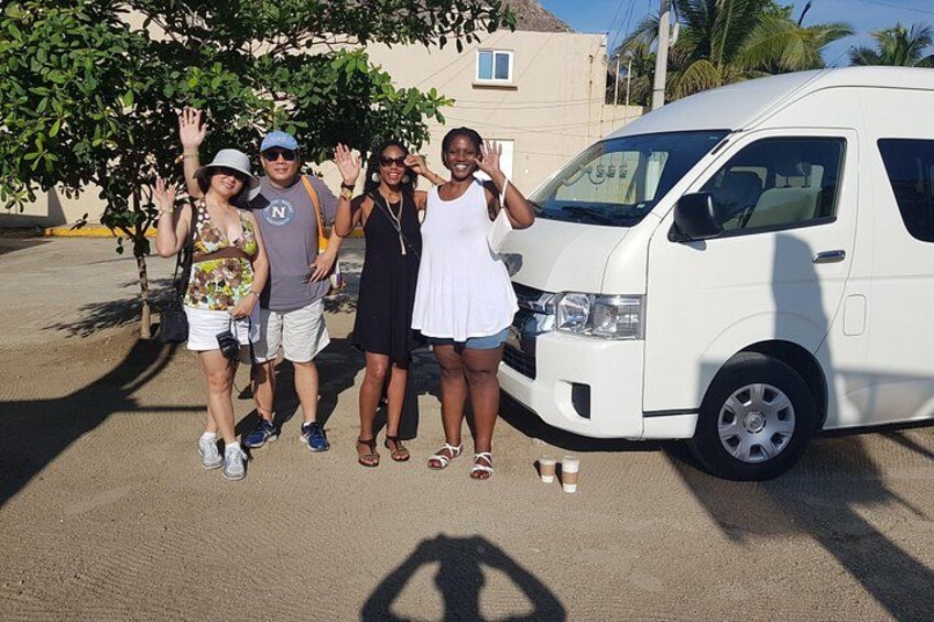 Un groupe de personnes posant devant un fourgon blanc, avec un arbre et un bâtiment en arrière-plan. 5