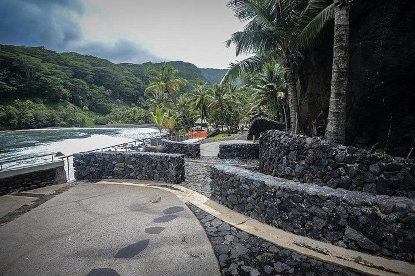 Un paseo marítimo con muros de piedra, palmeras y vistas al océano. 2