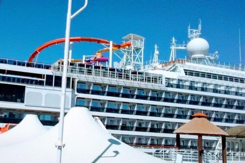 A large cruise ship with multiple decks and a water slide. 1