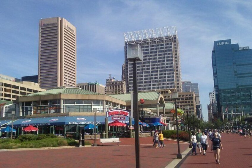 A city street with buildings, a pedestrian walkway, and people walking. 2