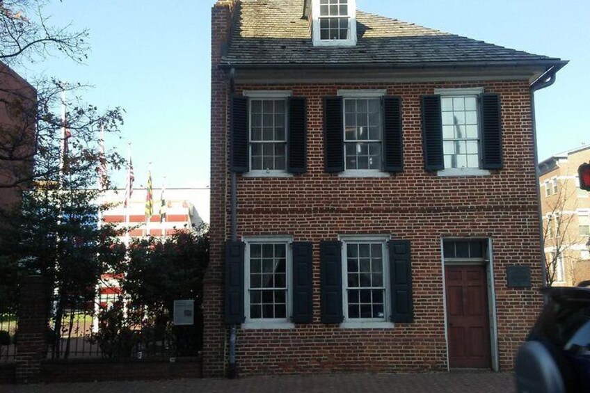 A brick building with black shutters and a red door. 3
