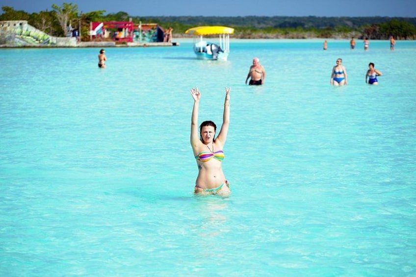 En person i bikini i en klarblå pool, med andra personer i bakgrunden. 2