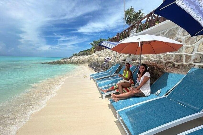 Une plage avec des chaises longues et des parasols, un ciel dégagé et une mer calme. 4