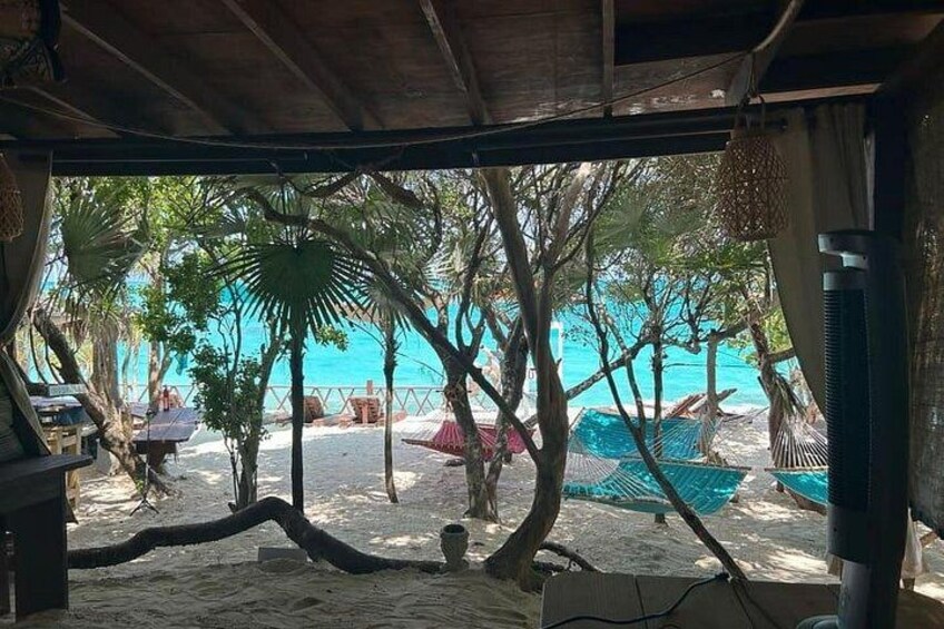 Une plage bordée de palmiers, une étendue de sable et des parasols de plage. 3